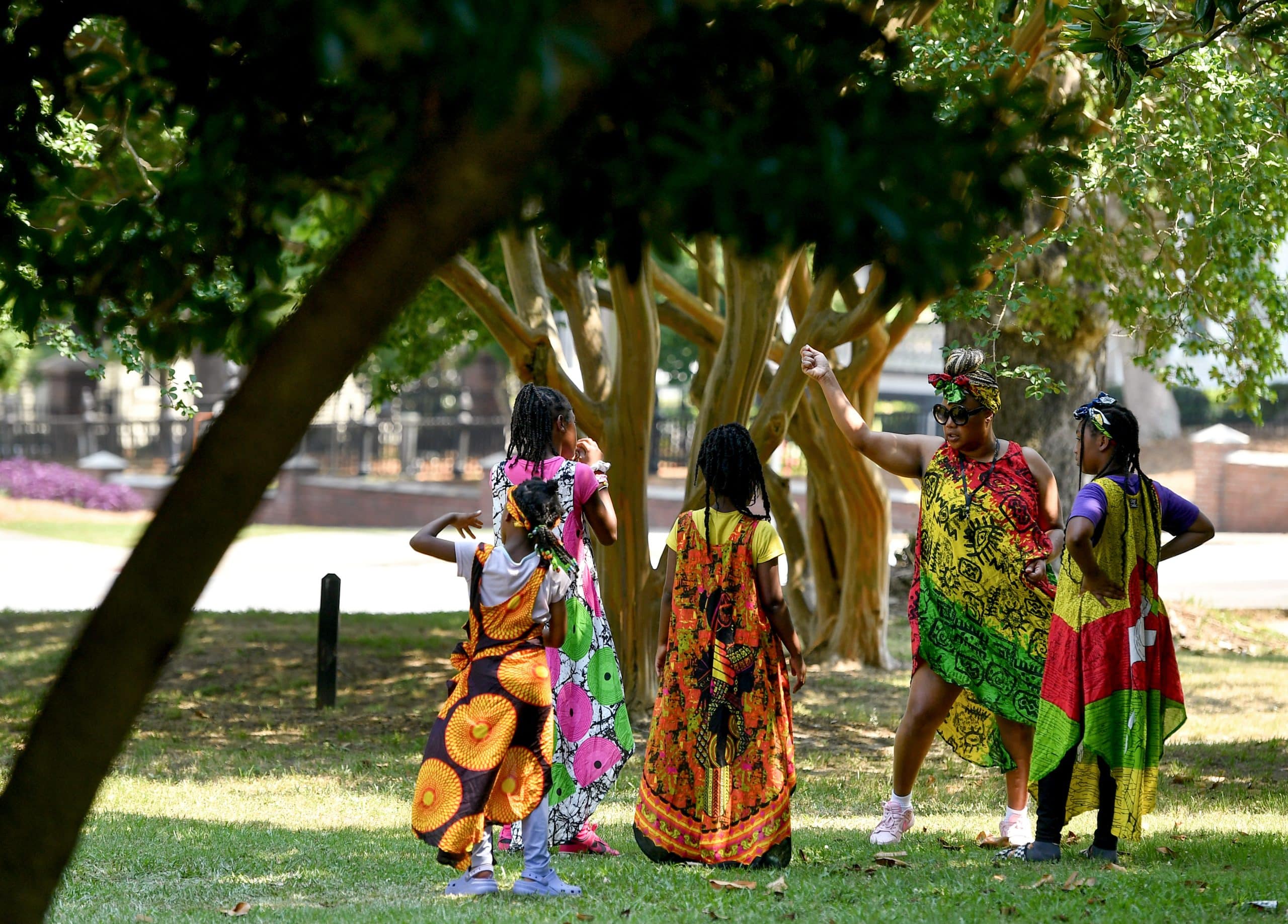 People in colorful garb dance in a park.