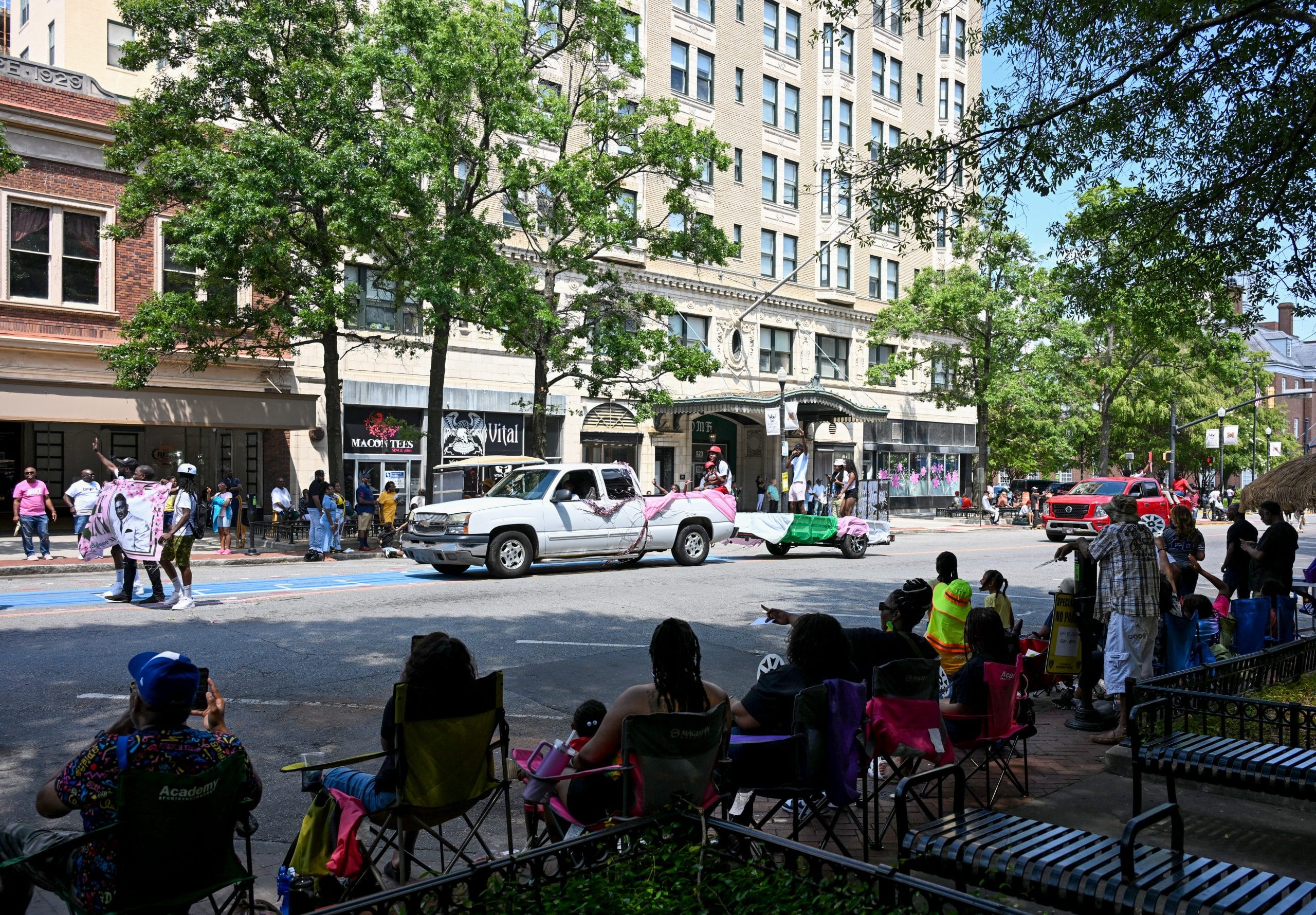 A truck pulling a trailer drives down a street in a parade.