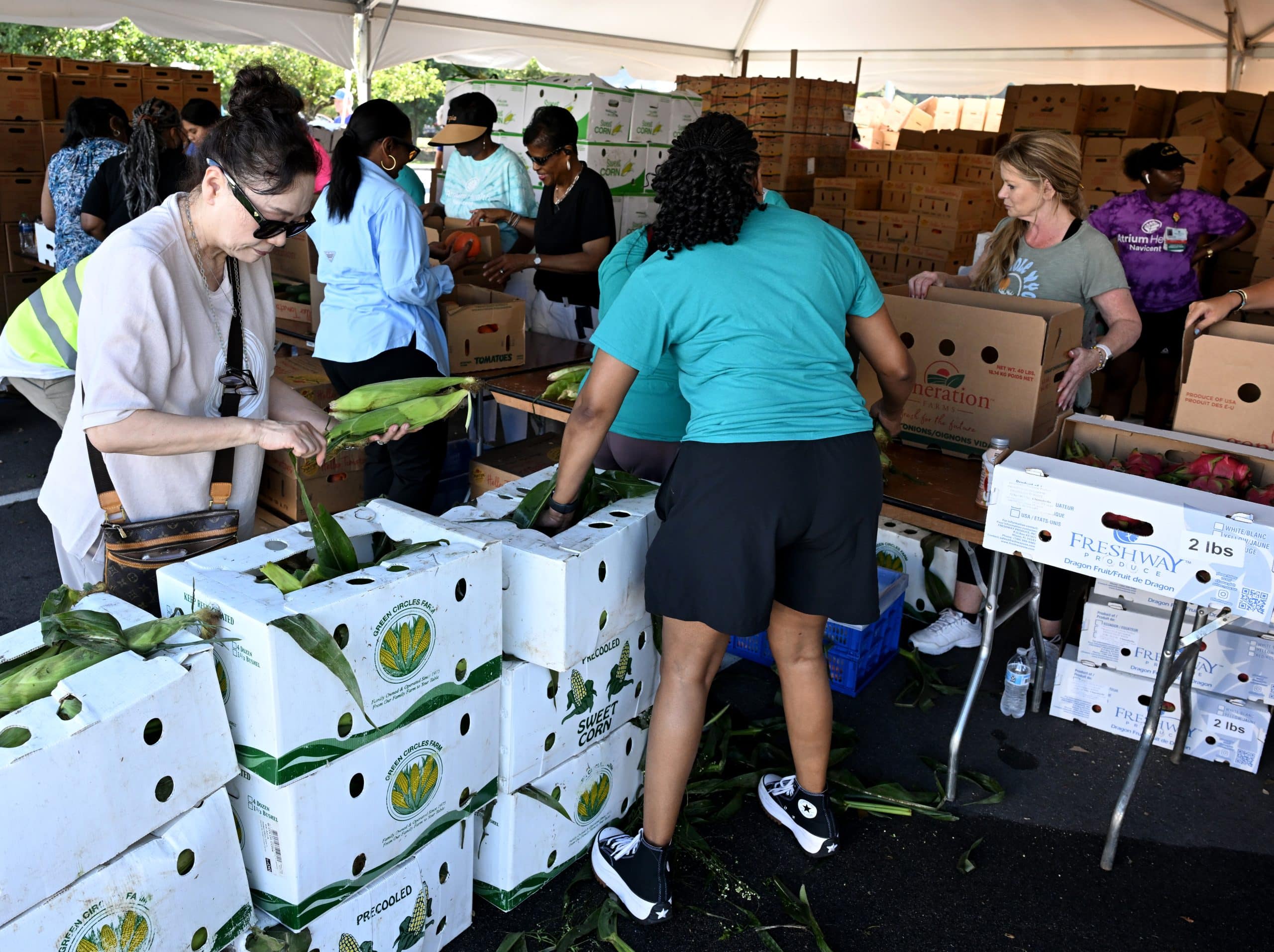 Volunteers put together a box of produce during a food distribution event.