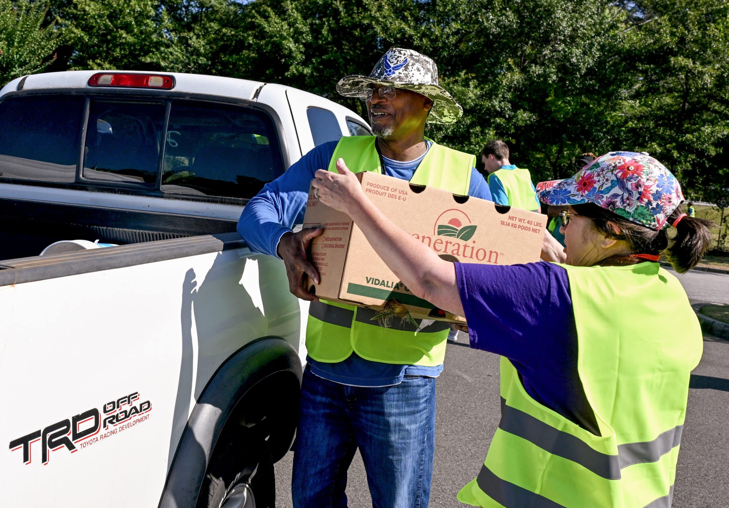 A volunteers places a box of produce into the back of a truck during a food distribution event.