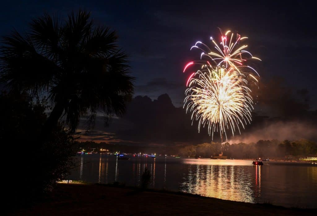 Fireworks go off over a lake.