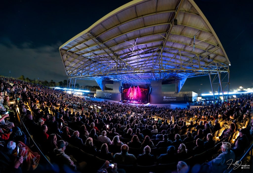 People stand in front of a large outdoor amphitheater at night.