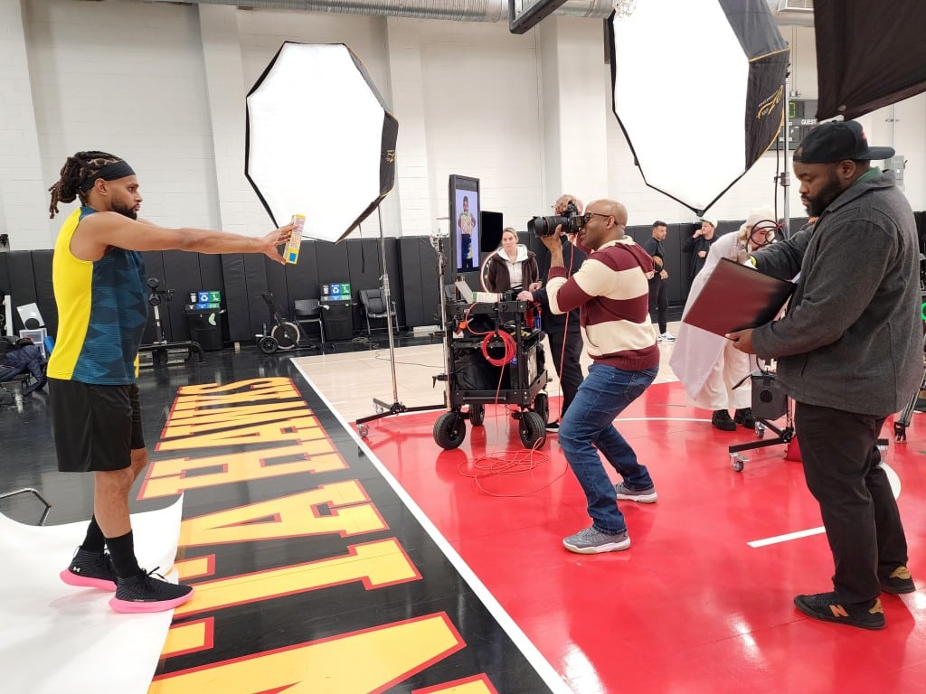 A professional photographer takes a picture of a basketball player in a photoshoot.