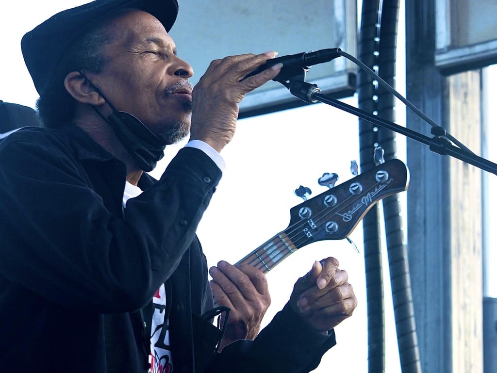 A man holding a guitar sings into a microphone.