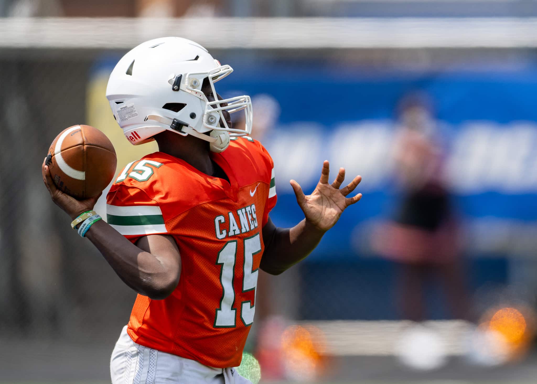A football player wearing a orange uniform with the number 15 throws the ball with no one around him.