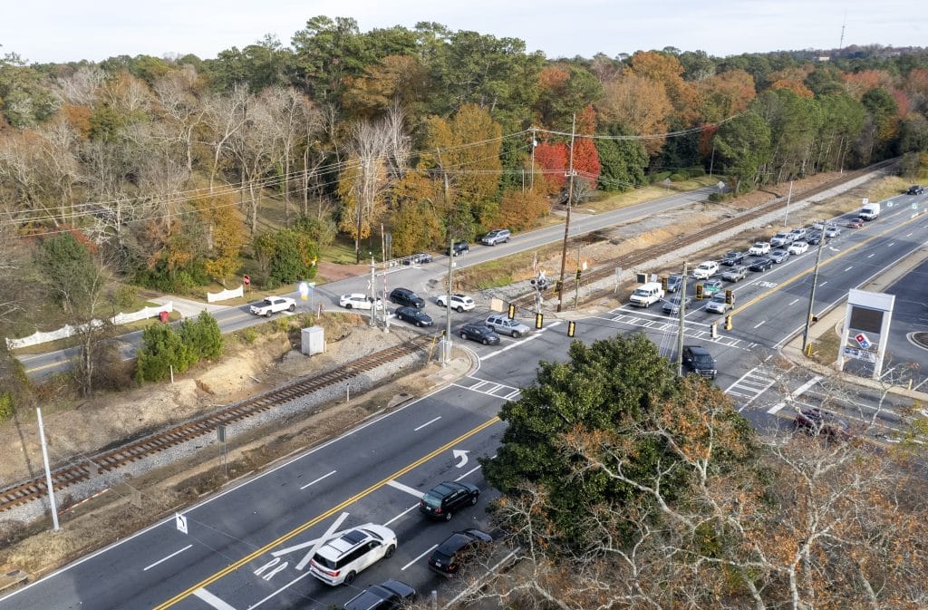 Traffic intersection with a stoplight and several cars near a treeline