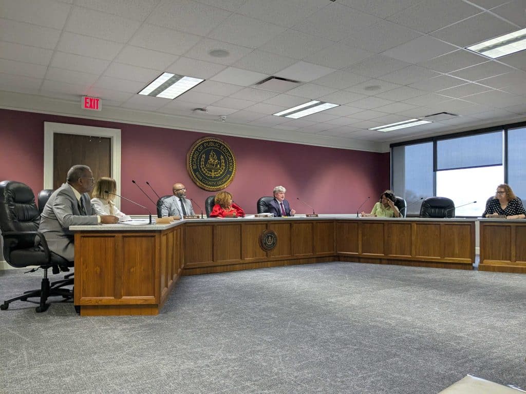 Board room with members seated in a u-shaped table.
